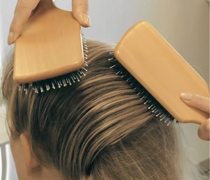 Blonde Haare werden mit zwei Paddle Bürsten gebürstet