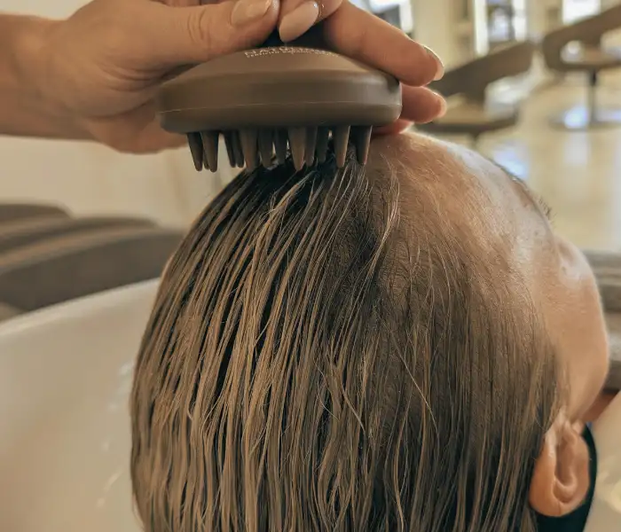 Haarepeeling wird mit einer speziellen Bürste auf das Haar aufgetragen