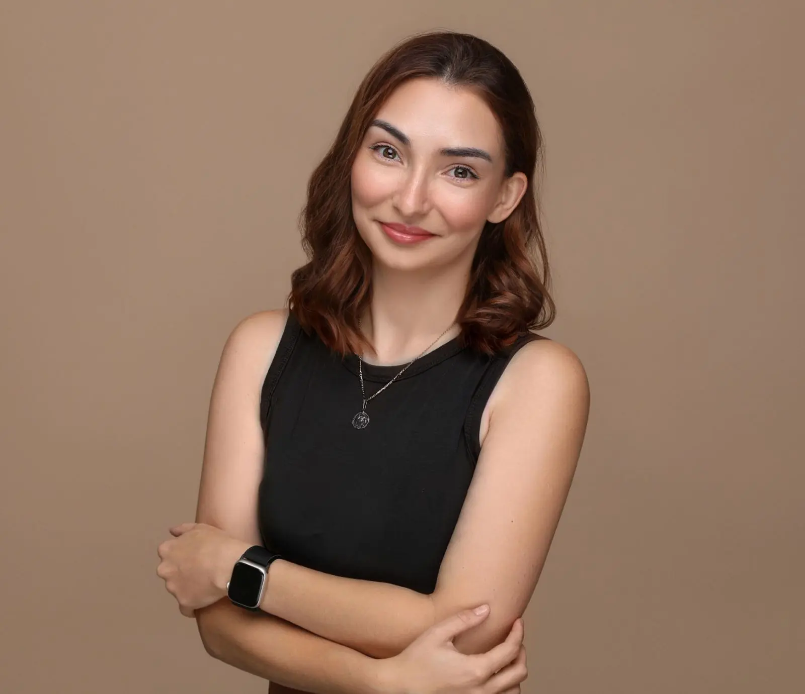 Mitarbeiterin Jessica. Freundliches Lächeln, schwarzes T-Shirt. Langes hellbraunes Haar. Tätowierung auf dem rechten Arm.