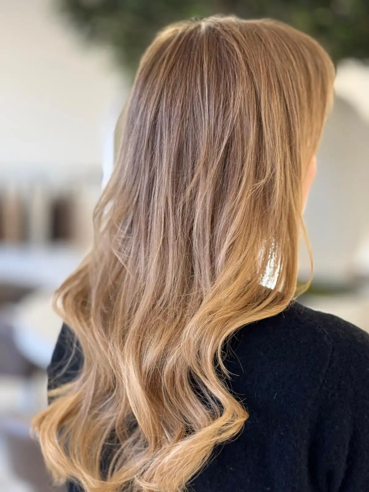 Mitarbeiterin Laura. Schwarze Bluse. Lange blonde, gewellte Haare